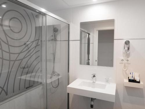 a white bathroom with a shower and a sink at Hotel Pasarela in Seville