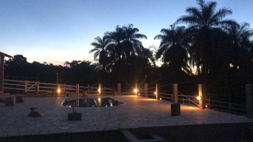 a night view of a swimming pool with palm trees at Chalés do Recanto in São João del Rei