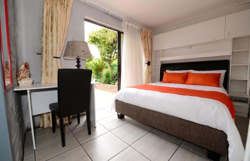 1 dormitorio con cama, escritorio y ventana en Corgi Guest House, en Johannesburgo