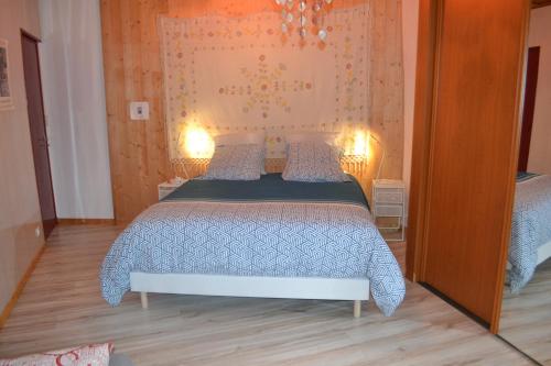 a bedroom with a bed with a blue comforter and two lamps at studio indépendant dans maison à la campagne in Égliseneuve-près-Billom