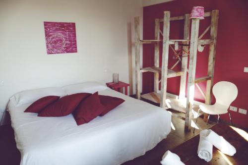 a bedroom with a white bed with red pillows and a ladder at Agriturismo Beatilla in Marmirolo