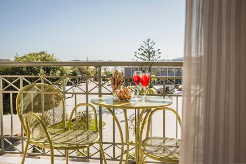 a table with chairs and wine glasses on a balcony at Ionian Plaza Hotel & Spa in Argostoli