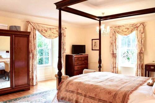 una camera con letto a baldacchino, cassettiera e finestre di Georgian Villa in Richmond on the River Swale a Richmond
