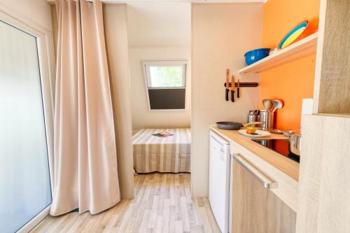 a small kitchen with orange walls and a window at San Benedetto Camping Relais in Peschiera del Garda