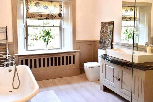 un bagno con lavandino e servizi igienici e due finestre di Georgian Villa in Richmond on the River Swale a Richmond