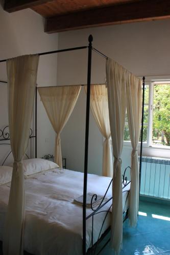 a bedroom with a canopy bed with curtains and a window at Agriturismo Tenuta La Muratella in Ponte Galeria