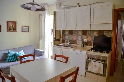 シラクーサにあるNoera Siracusaの白いキャビネット、テーブル、ソファ付きのキッチンが備わります。