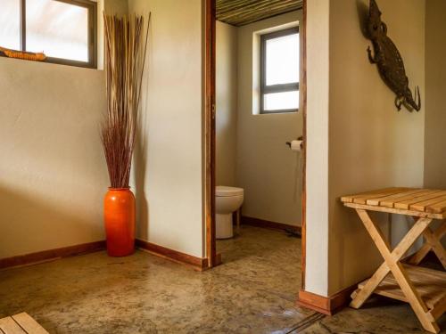 a bathroom with a toilet and a vase with grass at Imagine Africa Luxury Tented Camp in Balule Game Reserve