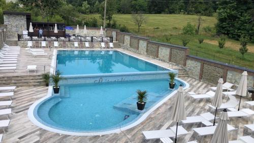 una gran piscina con sillas blancas en L’INVIDIA, en Novaci-Străini