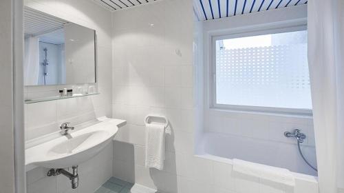 a white bathroom with a sink and a window at Hotel Francais in Luxembourg