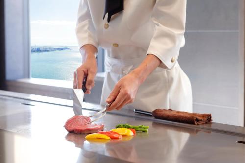 a person cutting up a piece of meat on a cutting board at Hotel Okura Kobe in Kobe