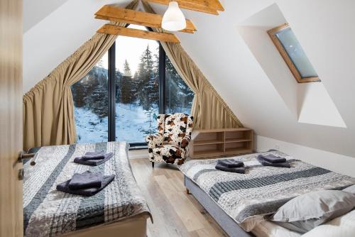 two beds in a room with a large window at Chaty Demänovská dolina in Liptovský Mikuláš