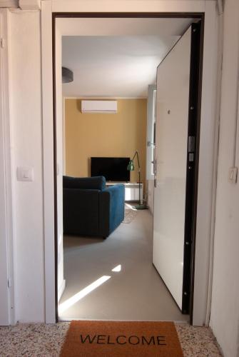 a door leading into a living room with a blue couch at MAJOR SISTERS, APPARTAMENTO VISTA LAGO DI LUGANO in Porto Ceresio
