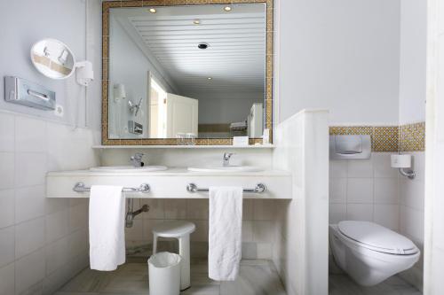 a bathroom with a sink and a mirror and a toilet at Hotel Duque de Najera in Rota