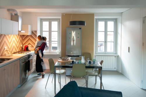 a woman standing in a kitchen with a table at MAJOR SISTERS, APPARTAMENTO VISTA LAGO DI LUGANO in Porto Ceresio