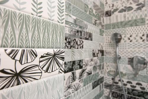 a bathroom with black and white tiles on the wall at MAJOR SISTERS, APPARTAMENTO VISTA LAGO DI LUGANO in Porto Ceresio