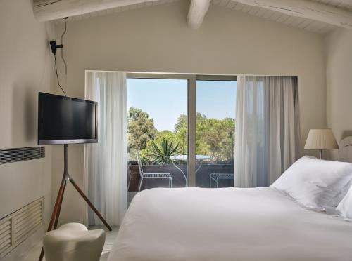 a bedroom with a bed and a large window at Ekies All Senses Resort, a Member of Design Hotels in Vourvourou