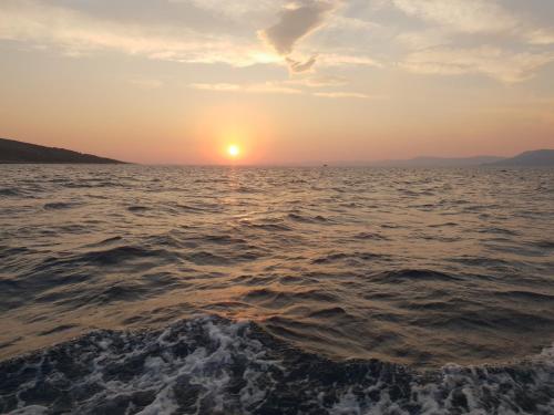 a sunset over the ocean on a boat at Cozy apartments with seafront terraces in Omiš