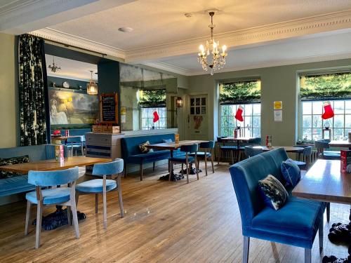 un restaurante con sillas azules, mesas y ventanas en Harts Head Hotel en Settle