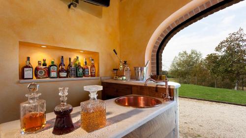 a bathroom with a sink and a mirror with bottles at GENIUS LOCI 6, Emma Villas in Collazzone
