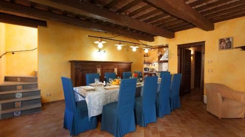a dining room with a table and blue chairs at GENIUS LOCI 6, Emma Villas in Collazzone