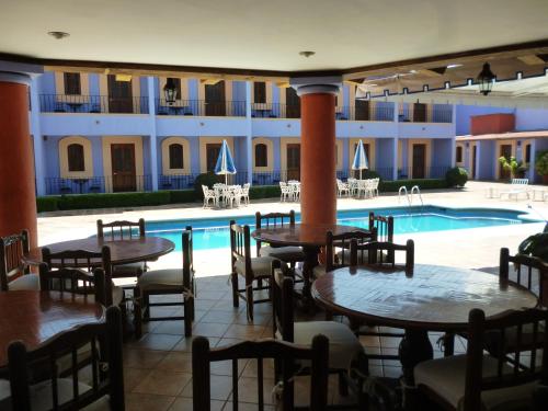 a hotel with tables and chairs next to a swimming pool at Santa Helena Plaza in Oaxaca City