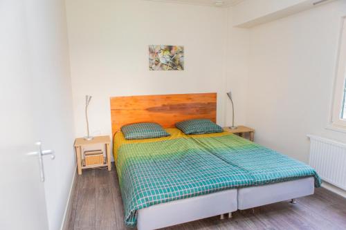 een slaapkamer met een bed met een houten hoofdeinde bij Landelijk appartement Friesland in Harich