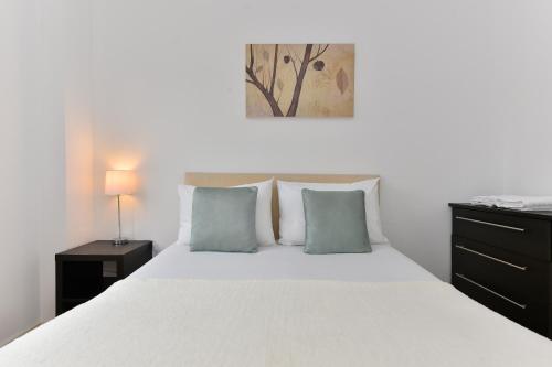1 dormitorio con 1 cama blanca y 2 almohadas azules en Holborn City Living, en Londres