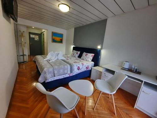 ein Schlafzimmer mit einem Bett und zwei weißen Stühlen in der Unterkunft Gostisce Jezero in Medvode