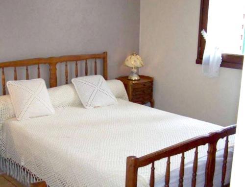 ein Schlafzimmer mit einem Bett mit weißer Bettwäsche und einer Lampe in der Unterkunft Maison de 2 chambres avec jardin clos et wifi a Marcillac la Croisille in Marcillac-la-Croisille
