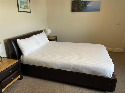a bedroom with a bed with white sheets and a table at An Stór Townhouse in Midleton