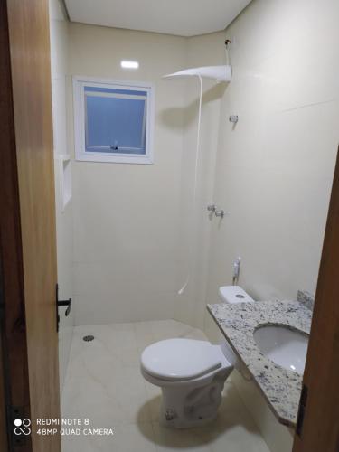 a bathroom with a toilet and a sink and a window at Pousada Village Maitinga in Bertioga