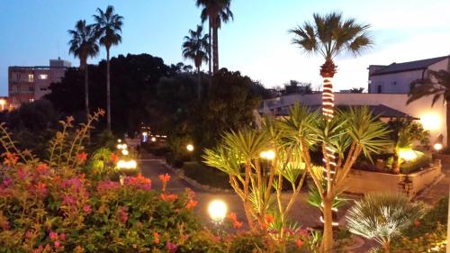 a view of a park at night with palm trees and lights at Grand Hotel Villa Politi in Siracusa
