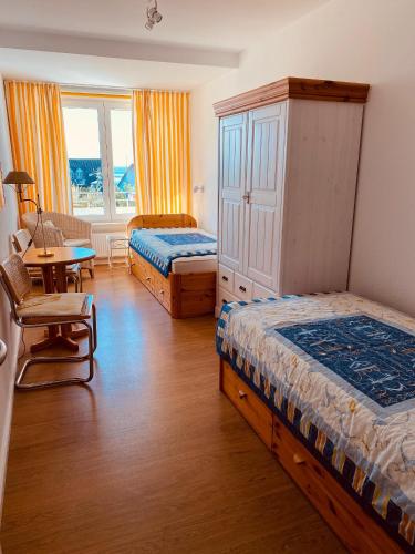 a bedroom with two beds and a desk and a table at Haus Halligblick Whg 20 in Wyk auf Föhr
