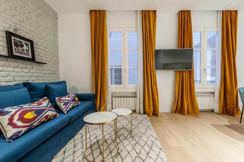 sala de estar con sofá azul y cortinas de color naranja en Hauzify I Apartamento Salamanca en Madrid