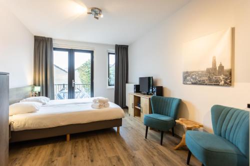 1 dormitorio con 1 cama y 2 sillas azules en UtrechtCityApartments – Weerdsingel en Utrecht