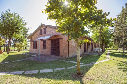 un arbre devant un bâtiment en briques dans l'établissement I Casali by La Principina, à Principina Terra