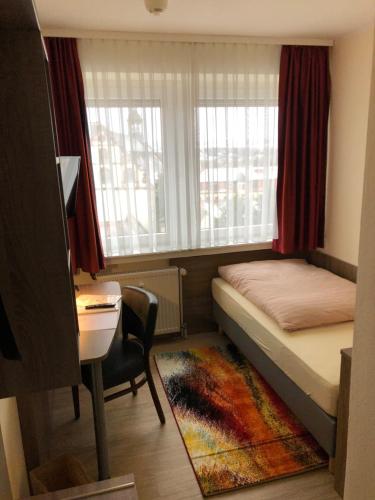 a bedroom with a bed and a desk and a window at Hotel Peterchens Mondfahrt in Fulda