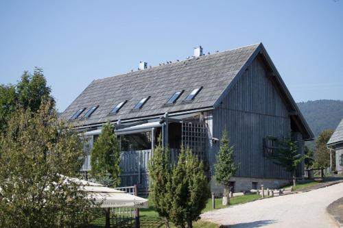 a large black barn with a gambrel roof at Ethno Houses Plitvice Lakes Hotel in Plitvica selo