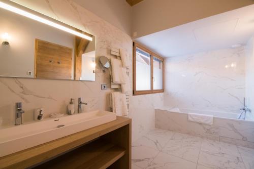 La salle de bains blanche est pourvue d'une baignoire et d'un lavabo. dans l'établissement Les Portes de Megève, à Praz-sur-Arly