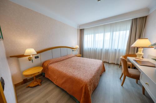 Pokój hotelowy z łóżkiem i biurkiem w obiekcie Perugia Plaza Hotel w mieście Perugia