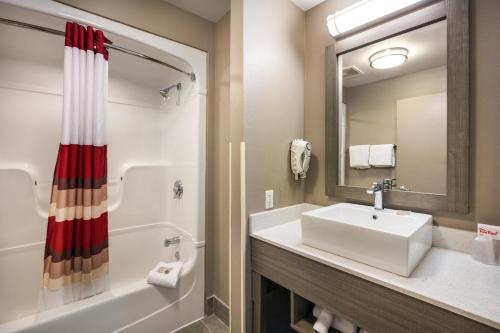 La salle de bains est pourvue d'un lavabo, d'une baignoire et d'une douche. dans l'établissement Red Roof Inn PLUS+ Boston - Logan, à Saugus