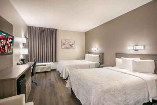 a hotel room with two beds and a television at Red Roof Inn PLUS+ Boston - Logan in Saugus