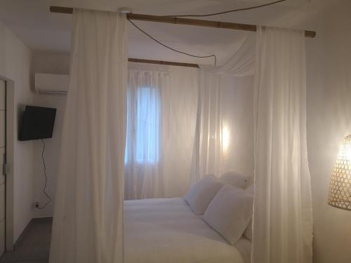 a bedroom with a bed with white curtains and a window at Une Nuit à Bali - Appartement cocooning in Solliès-Toucas