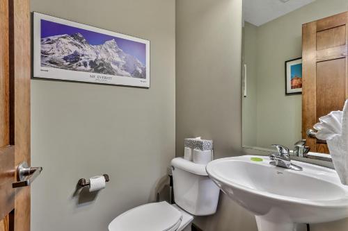 a bathroom with a sink and a toilet and a mirror at Spacious Mountain 2 Bedroom with Hot tub managed by Little Sister Getaways in Canmore