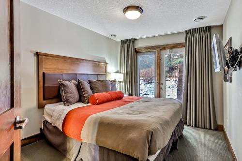 a bedroom with a large bed with an orange pillow on it at Fenwick Vacation Rentals Spacious Mountain 2 Bedroom with Hot tub in Canmore