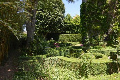 a garden with green hedges and a pond at Maison d'hôtes - Les Tillets in Bois-Sainte-Marie