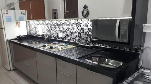 a kitchen with a sink and a microwave at Apto no Ed. Alexandra I in Guarujá