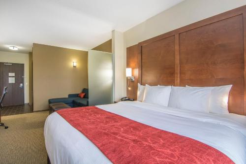 a hotel room with a large bed with a red blanket at Comfort Suites Regina in Regina