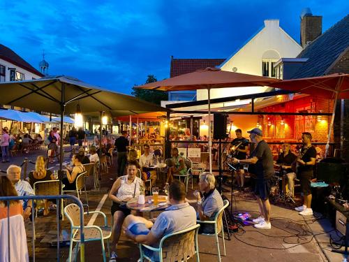 a group of people sitting at tables in an outdoor restaurant at Uniek huis onderaan de duinen -veel privacy- eigen parkeerplaats in Domburg